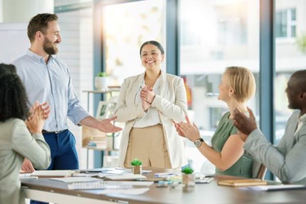 Une femme félicitée pour son travail par des collaborateurs
