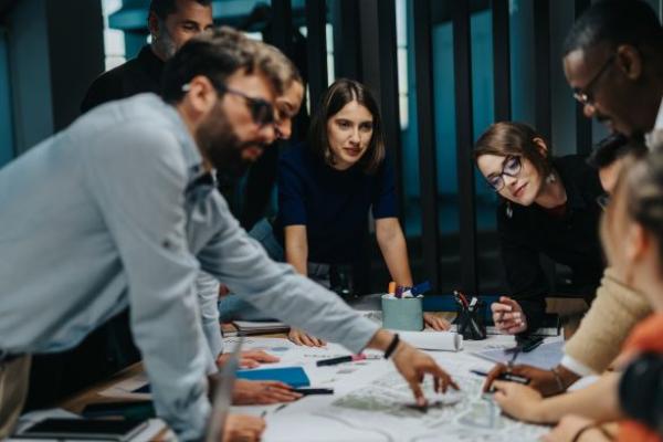 Manager et collaborateurs collaborant autour d’un écran affichant des modules de formation en ligne, symbolisant une culture d’apprentissage en entreprise