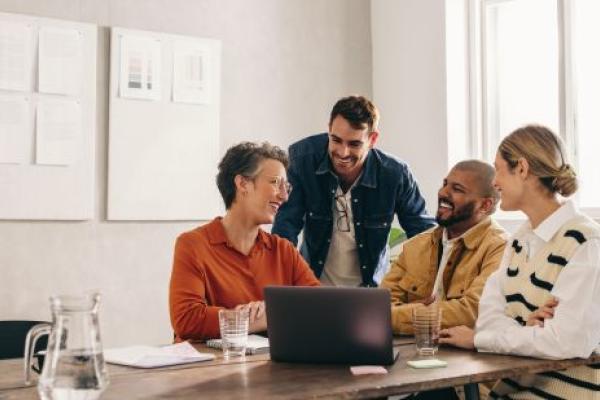 Manager présentant une stratégie de collaboration à des membres d’équipe de cultures et nationalités diverses réunis autour d’une table de réunion